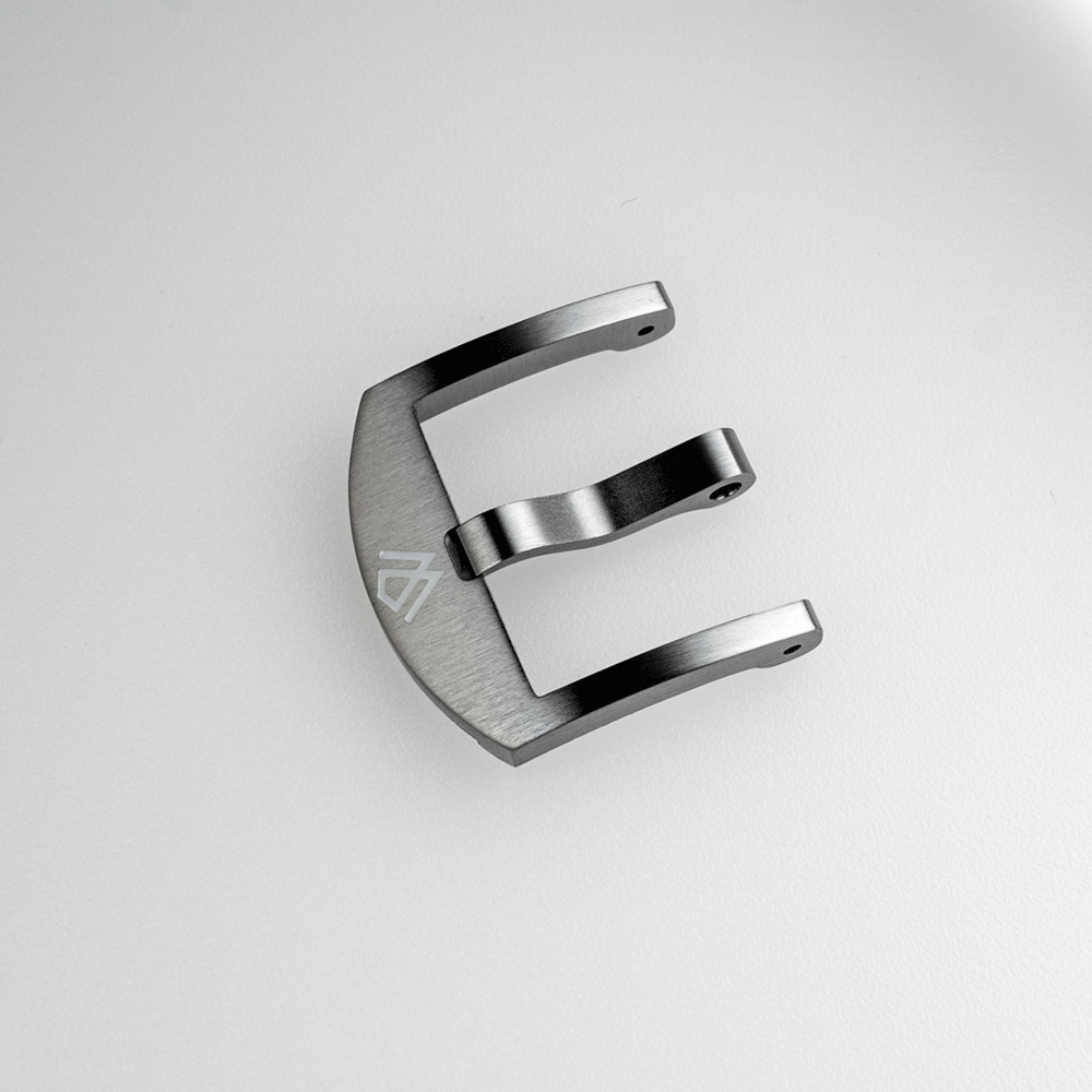 A silver watch buckle with the letter e on it