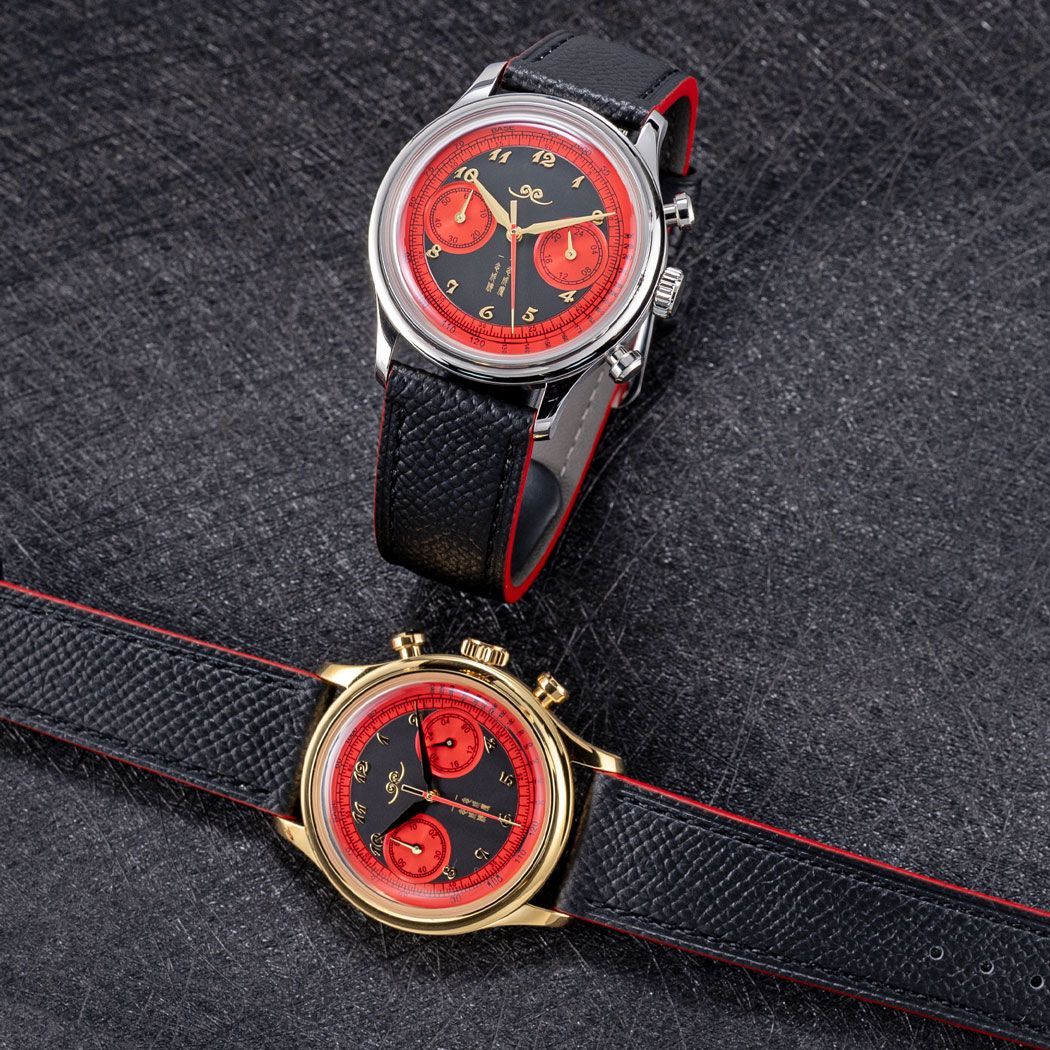 Two chronograph watches with black and red dials and black leather straps, displayed on a textured dark background.