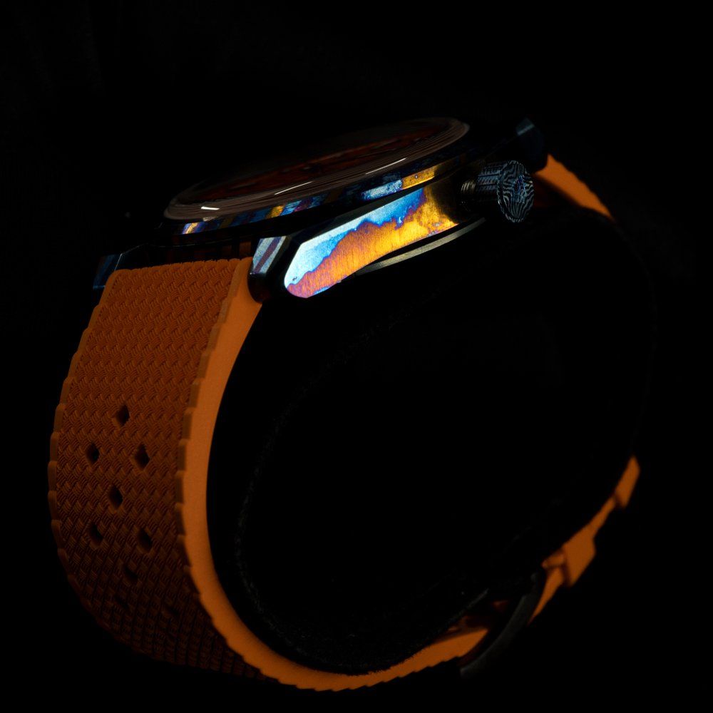 A watch with an orange band is lit up in the dark