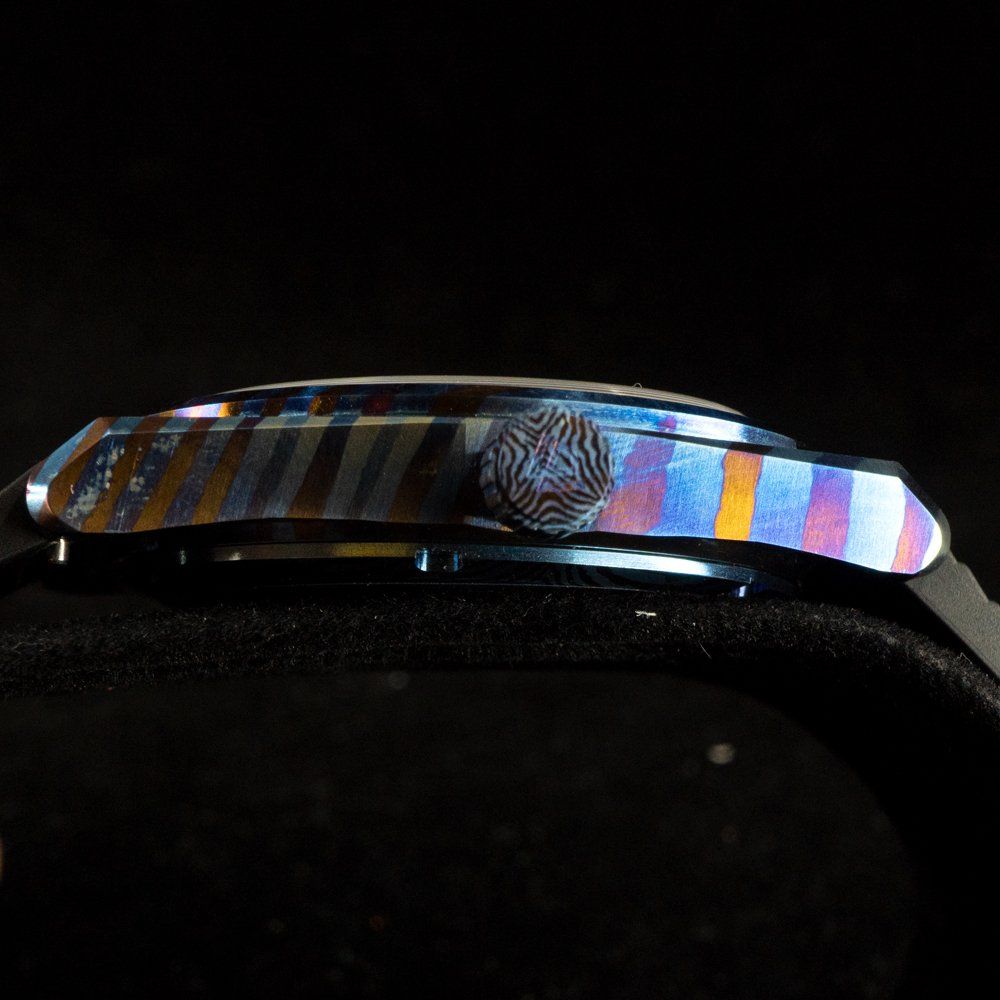 A close up of the side of a watch on a black background.