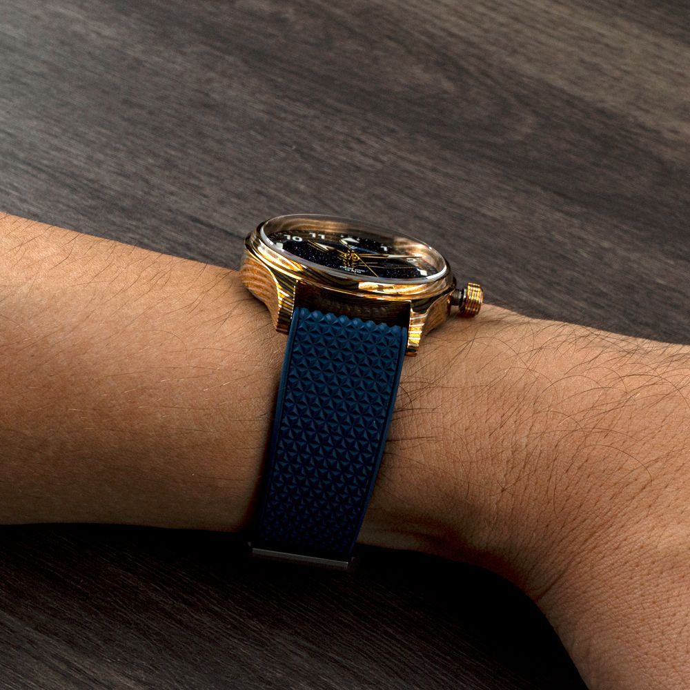 A person is wearing a gold watch with a blue band on their wrist.