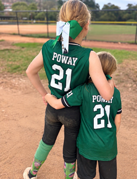 Baseball glove with ball on green grass, with blurred baseballs in the background.