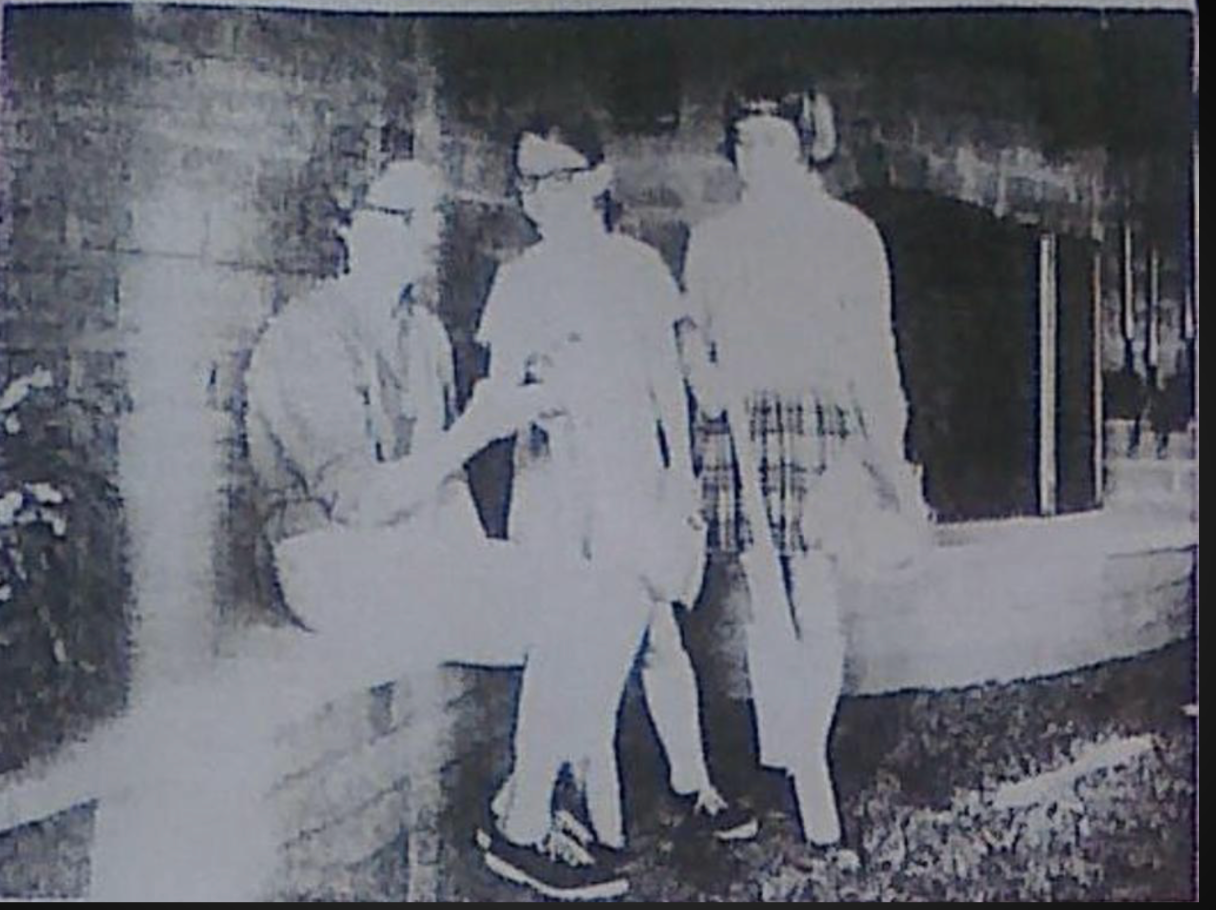 Three people standing outside a building in a black-and-white photo.
