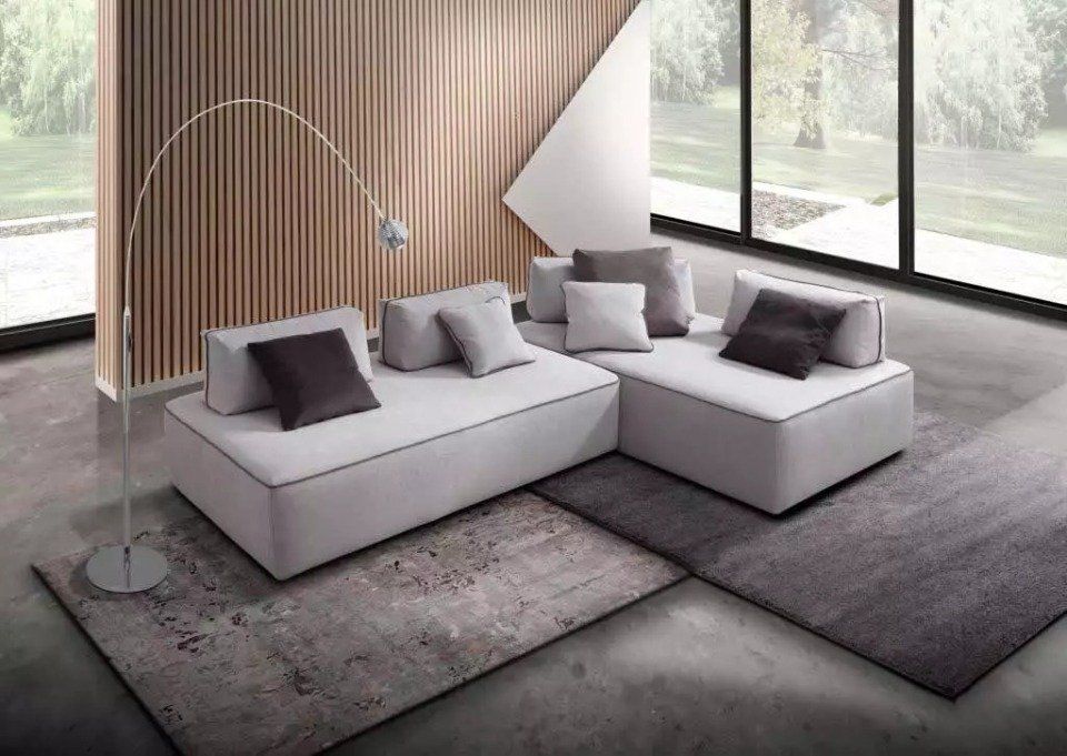 divano angolare color panna con cuscini scuri e chiari