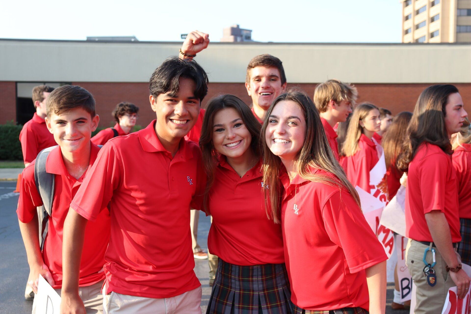 Group of smiling people in red shirts standing together outdoors at an event