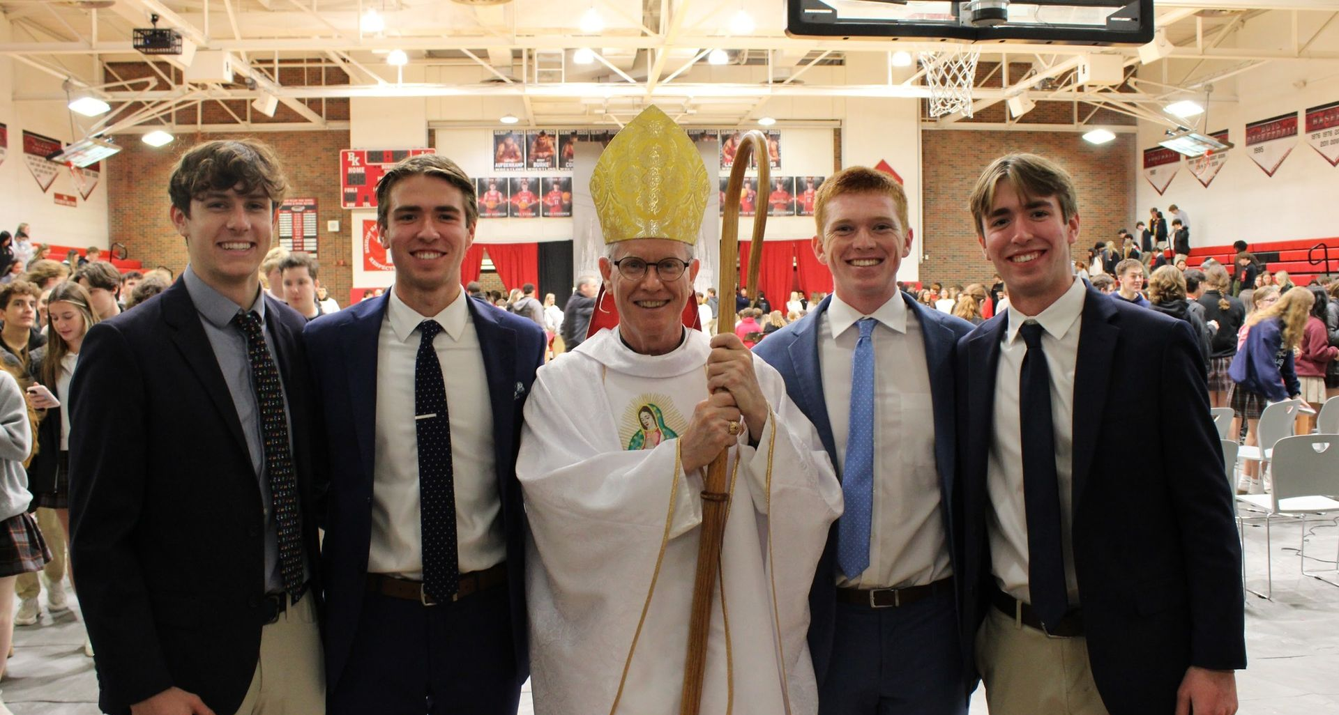 Bishop with staff poses with students in suits at All-School Mass.