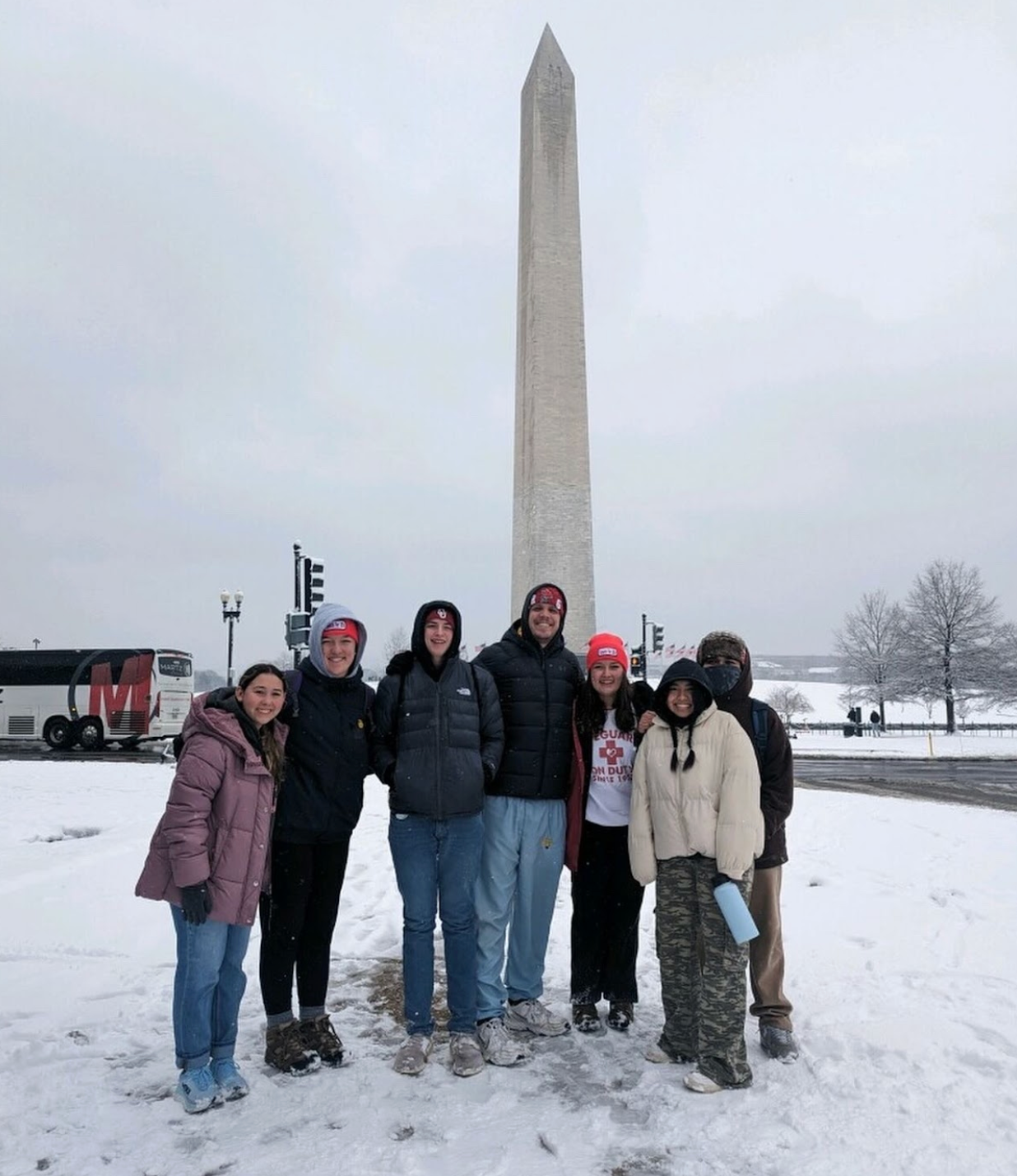 Group poses with Washington Monument in snowy weather.