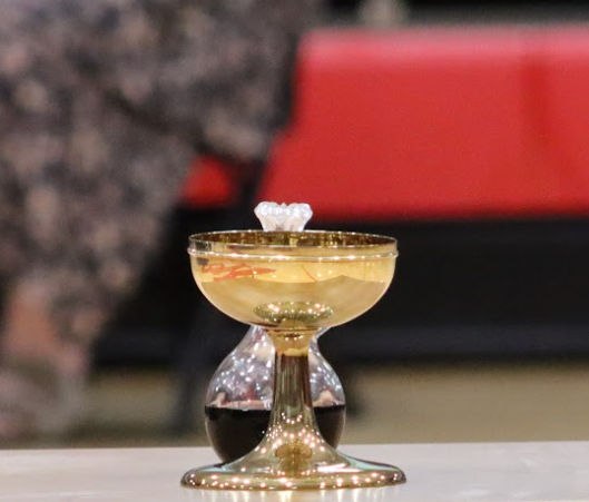 Golden chalice with a white wafer, containing liquid, and a wine decanter.