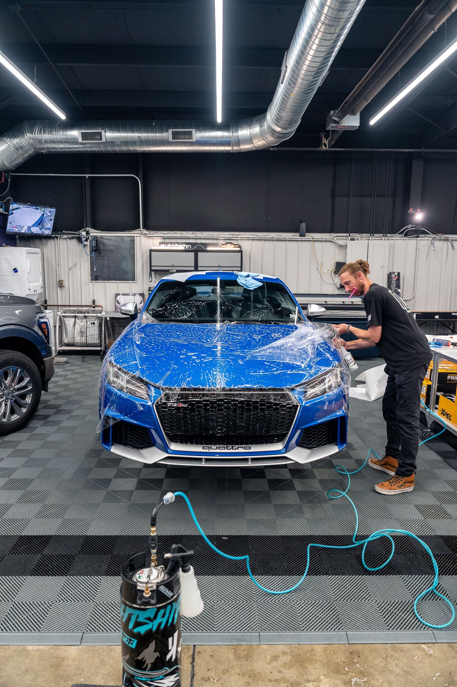 A blue sports car is parked on a lift in a garage.