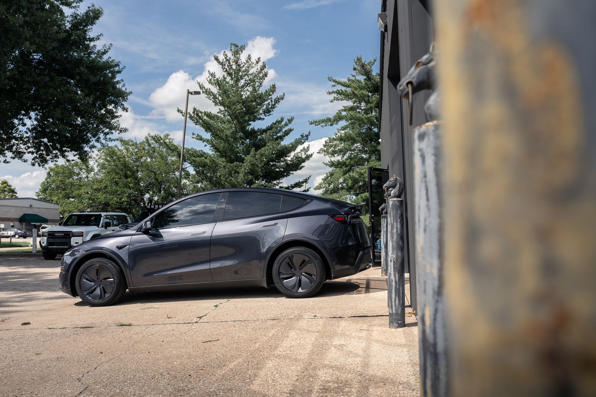 A man is wrapping a tesla model x in a matte black wrap.