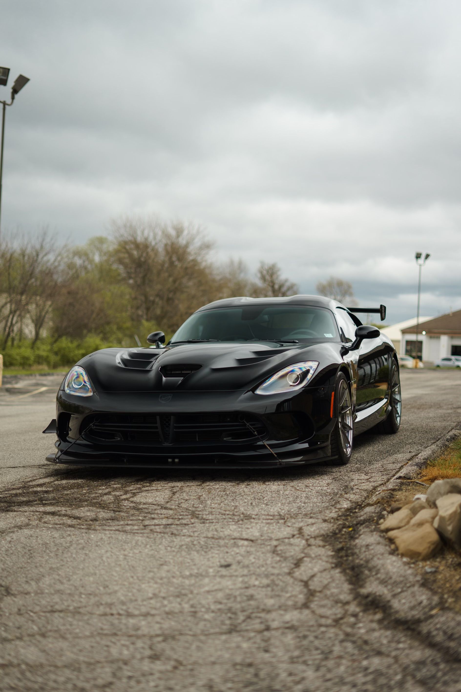 A black dodge viper is parked on the side of the road.