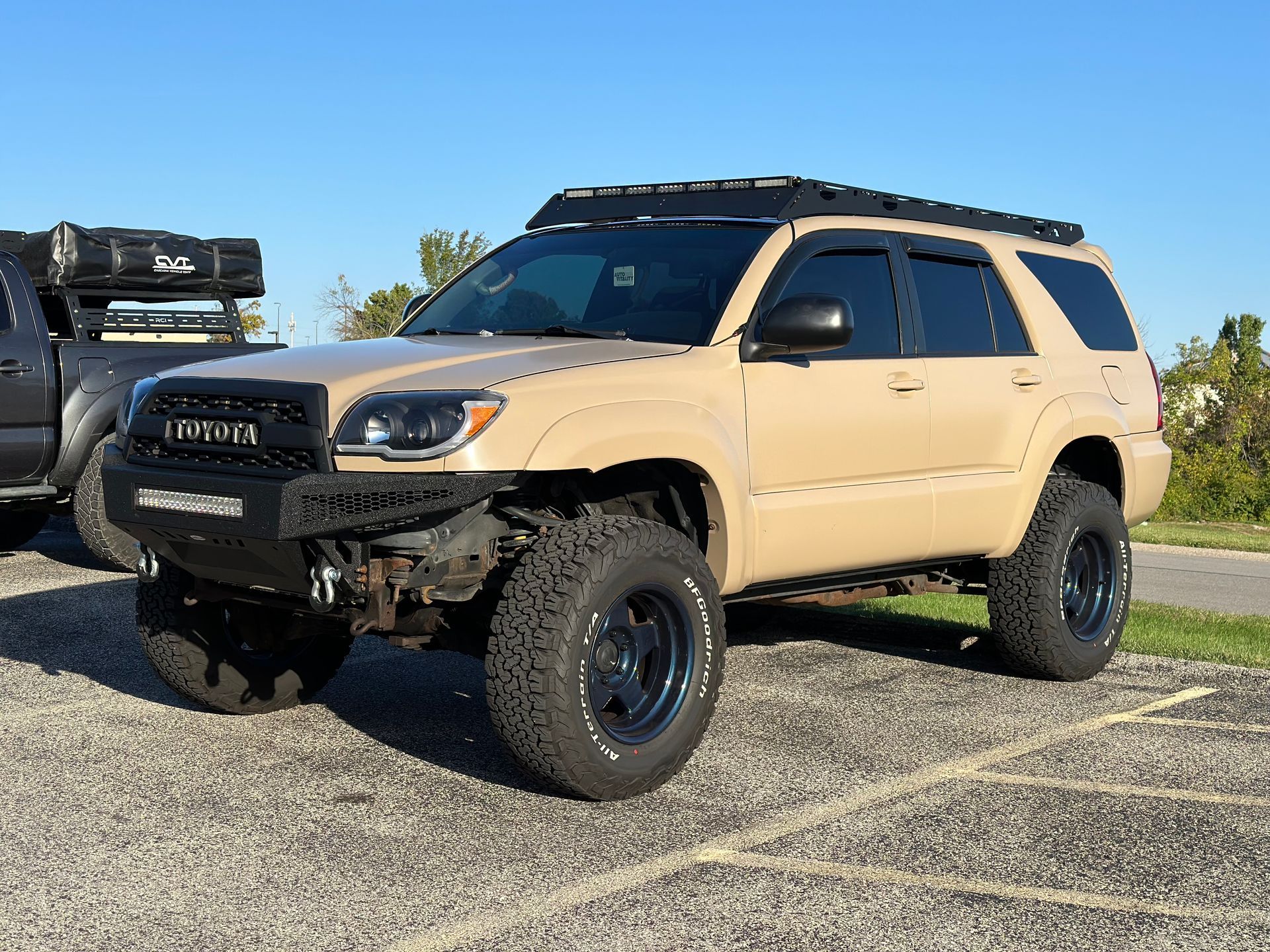 A tan toyota 4runner is parked in a parking lot.