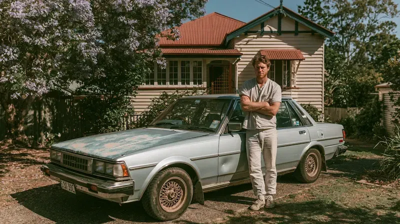 A man stands beside an unroadworthy car hoping to sell it as-is