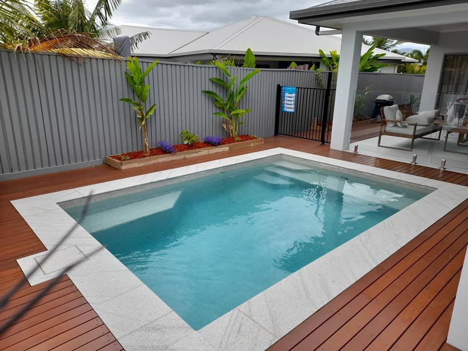 A Small Swimming Pool Is Surrounded by A Wooden Deck and A Fence — Pools Plus NQ in Port Douglas, QLD