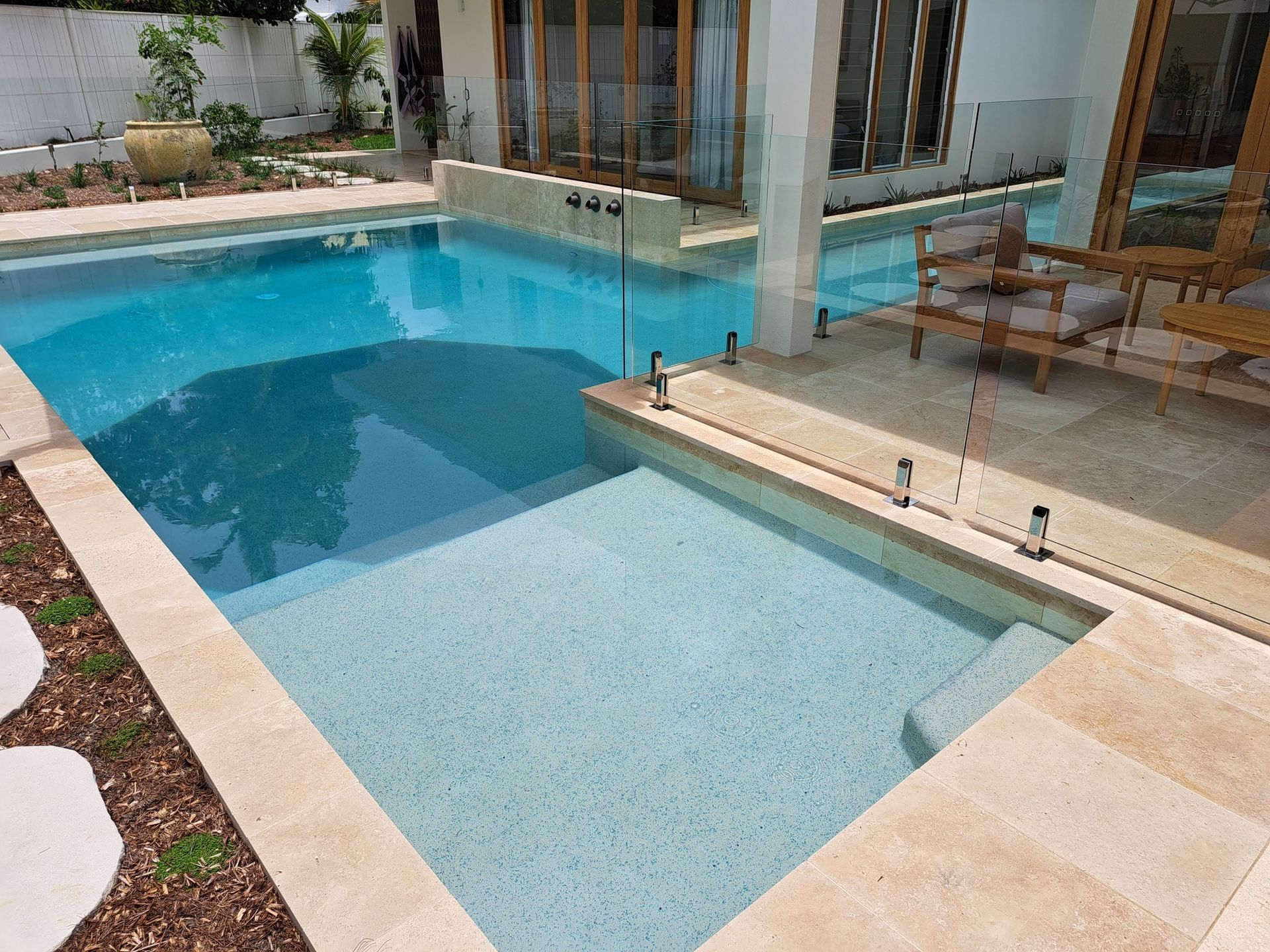 A Large Swimming Pool with A View of The Ocean and A House in The Background — Pools Plus NQ in Kewarra Beach, QLD
