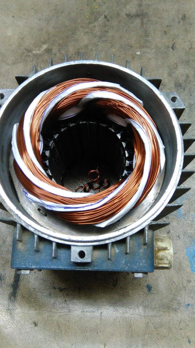 Primer plano de una bobina de cobre enrollada dentro de una carcasa metálica gris de un motor o transformador.