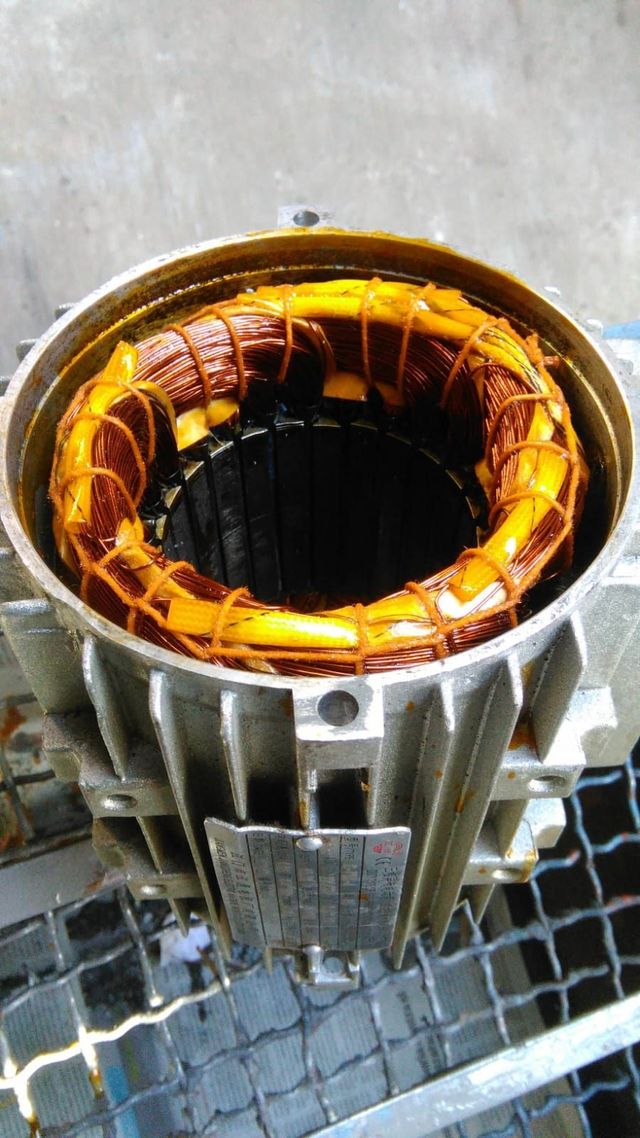 Estator de motor eléctrico abierto con bobinados de cobre naranja y orificio central oscuro