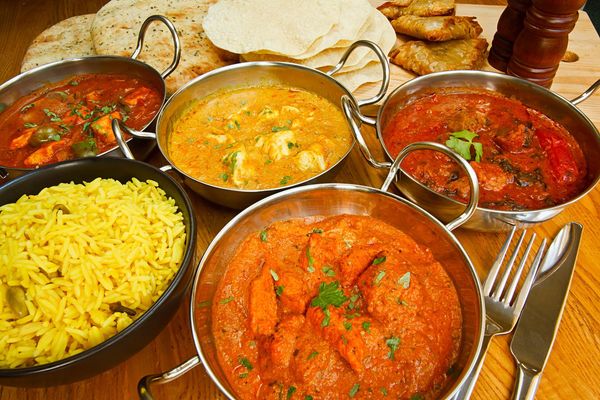 Assortment of Indian dishes, including curries, rice, and bread, served in copper bowls.