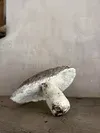 A white mushroom-like object lying on its side against a plain wall and floor.