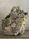 Rough gray-green rock with a jagged, weathered surface on a plain background