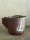 Brown ceramic cup on a light surface against a plain wall
