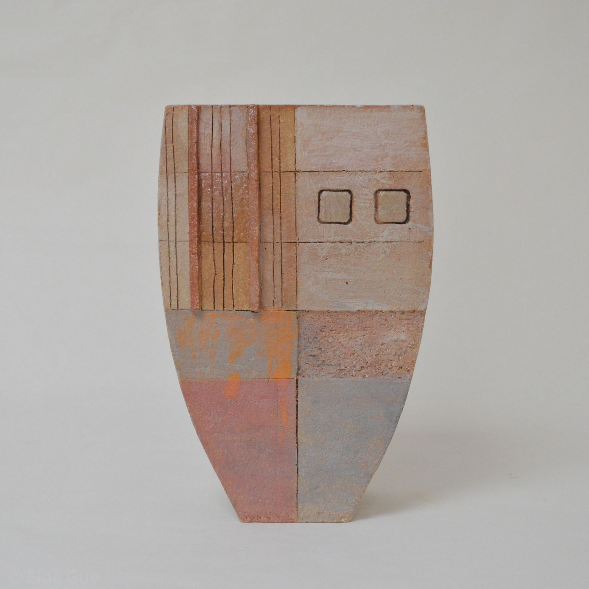 Abstract ceramic vase with muted tan, peach, and gray panels and two square cutout details near the top