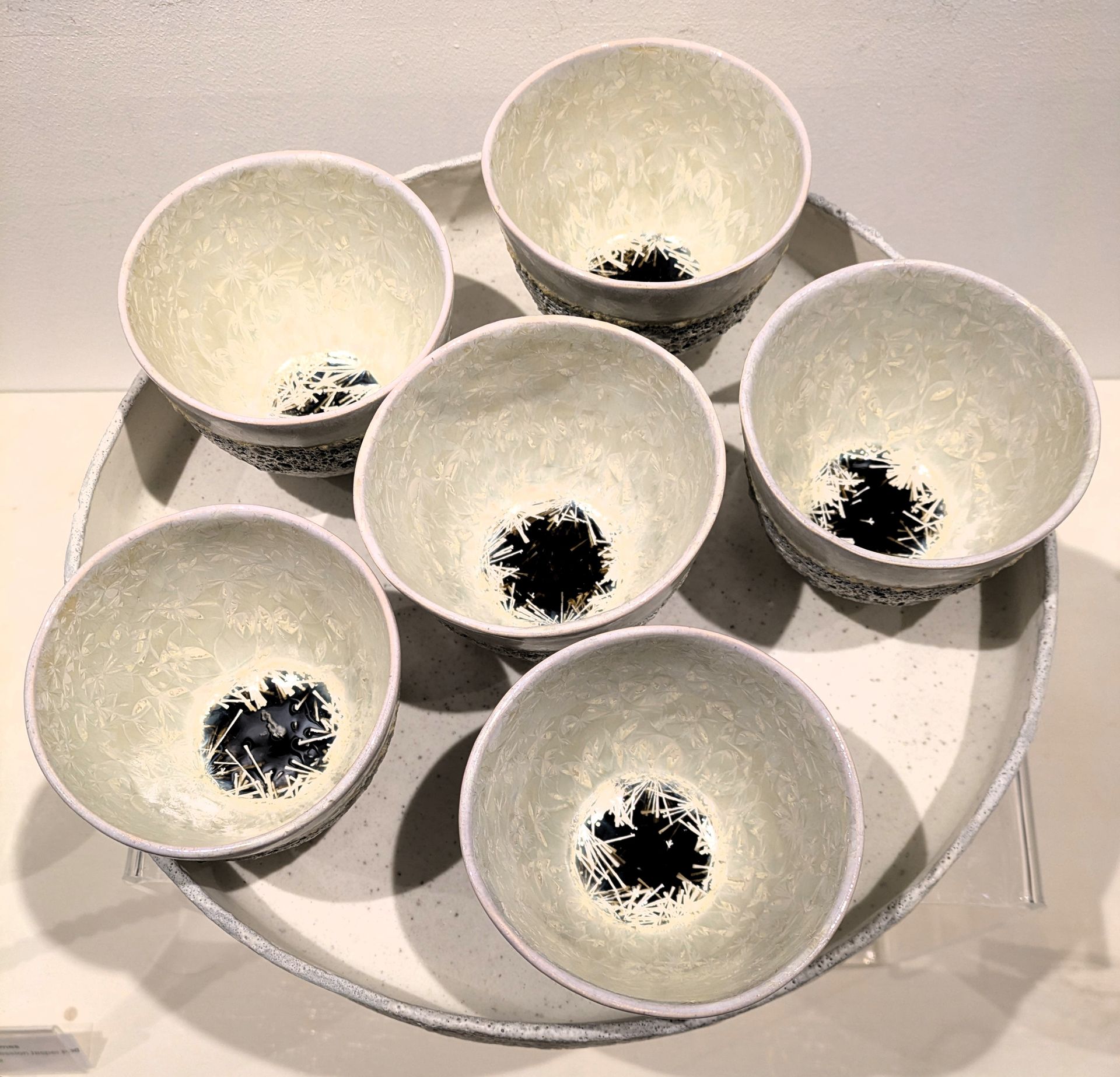 A group of white bowls with black spots on them are sitting on a white plate.