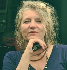 A woman in a blue shirt is holding a flashlight in her hand.