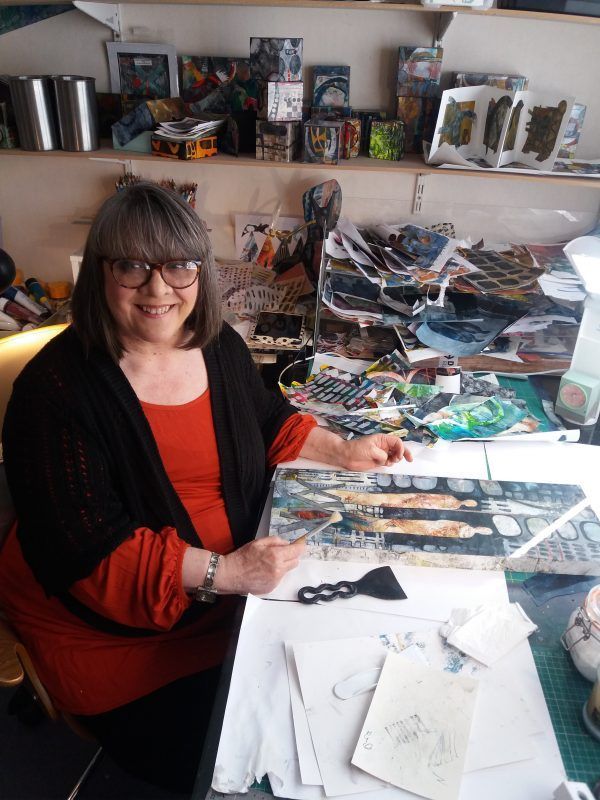 A woman is sitting at a table with a painting on it.