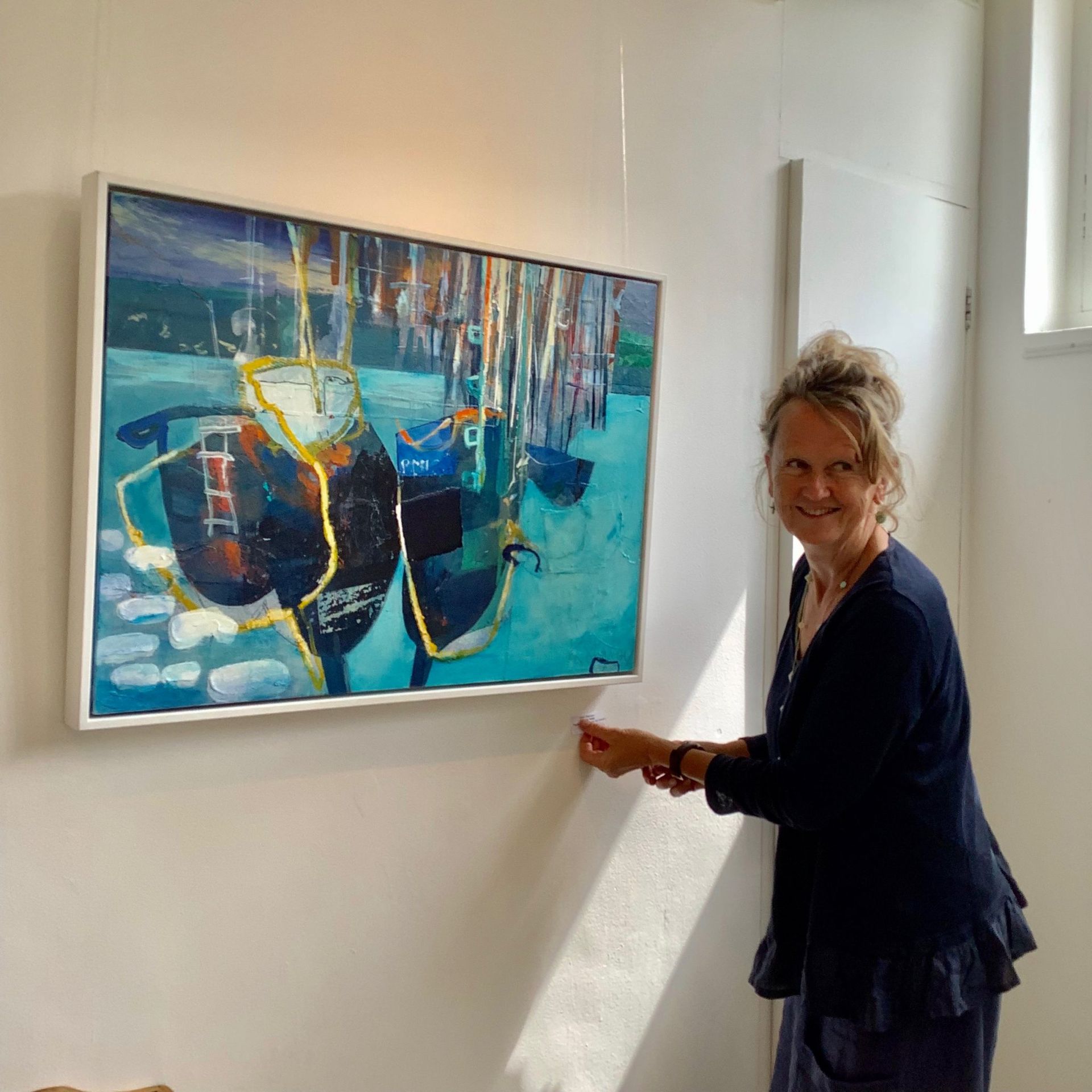 A woman is standing in front of a painting on a wall