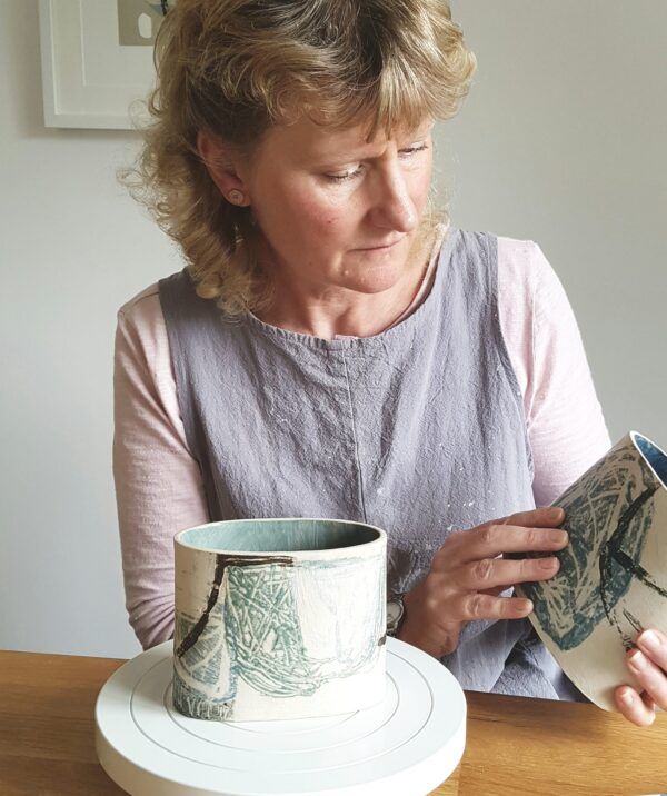 A woman is sitting at a table looking at a vase