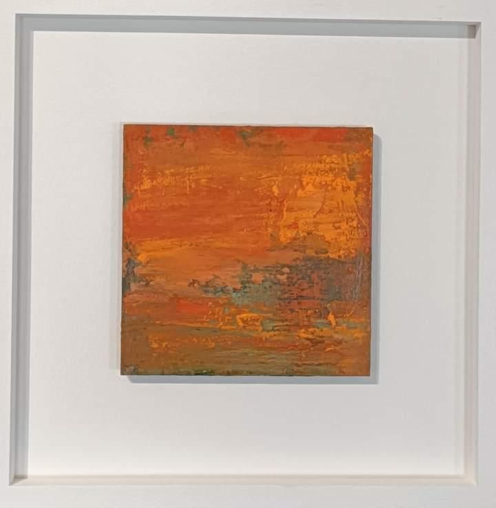 a painting in a white frame is hanging on a wall .