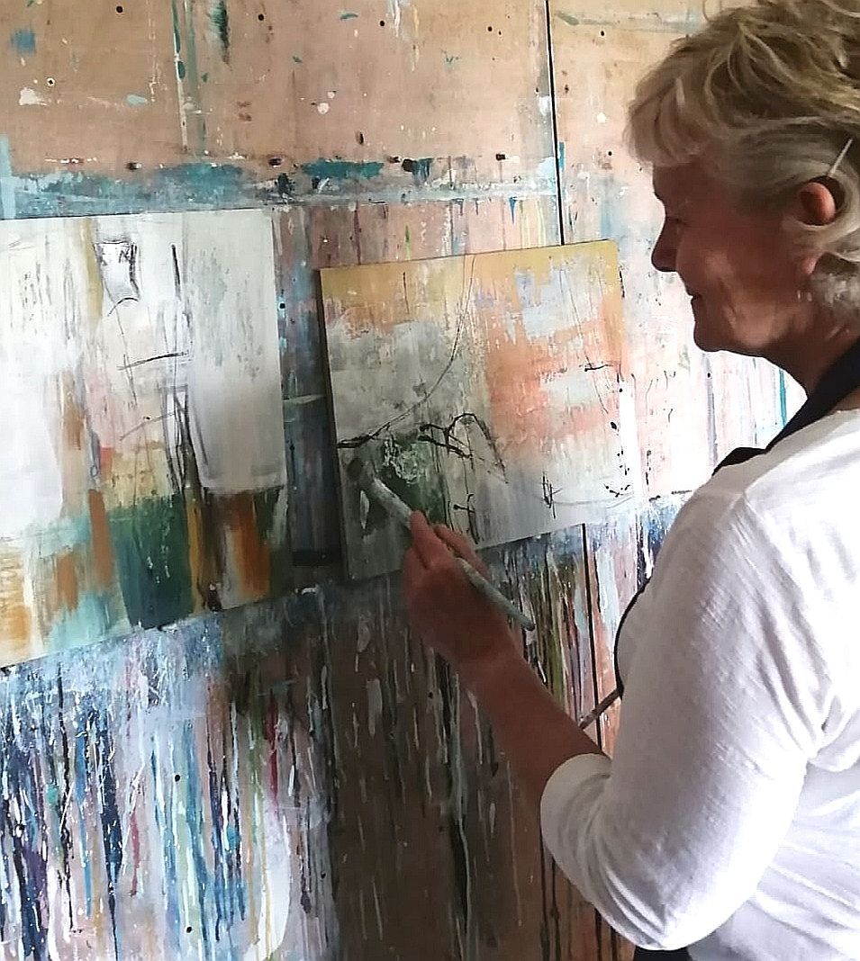 A woman is painting on a wall with a brush