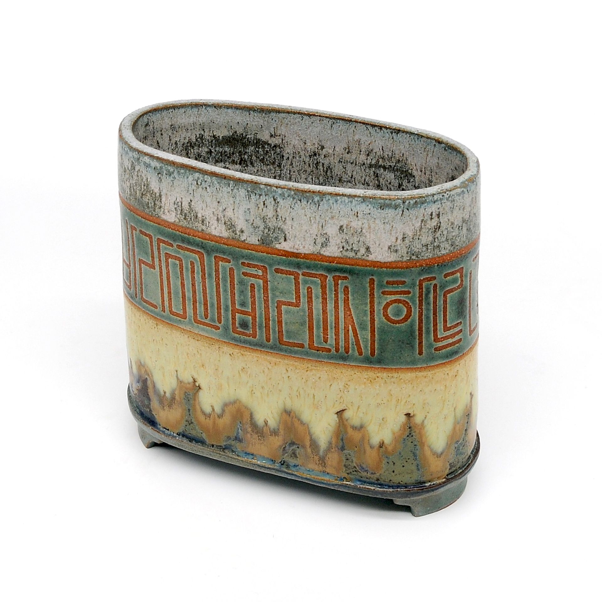 A ceramic container with a green border and a chinese symbol on it