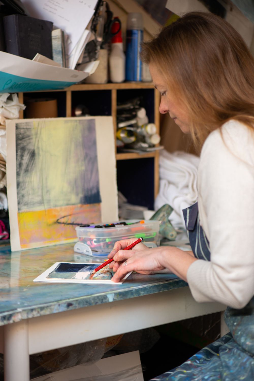 A woman is sitting at a table painting a picture.