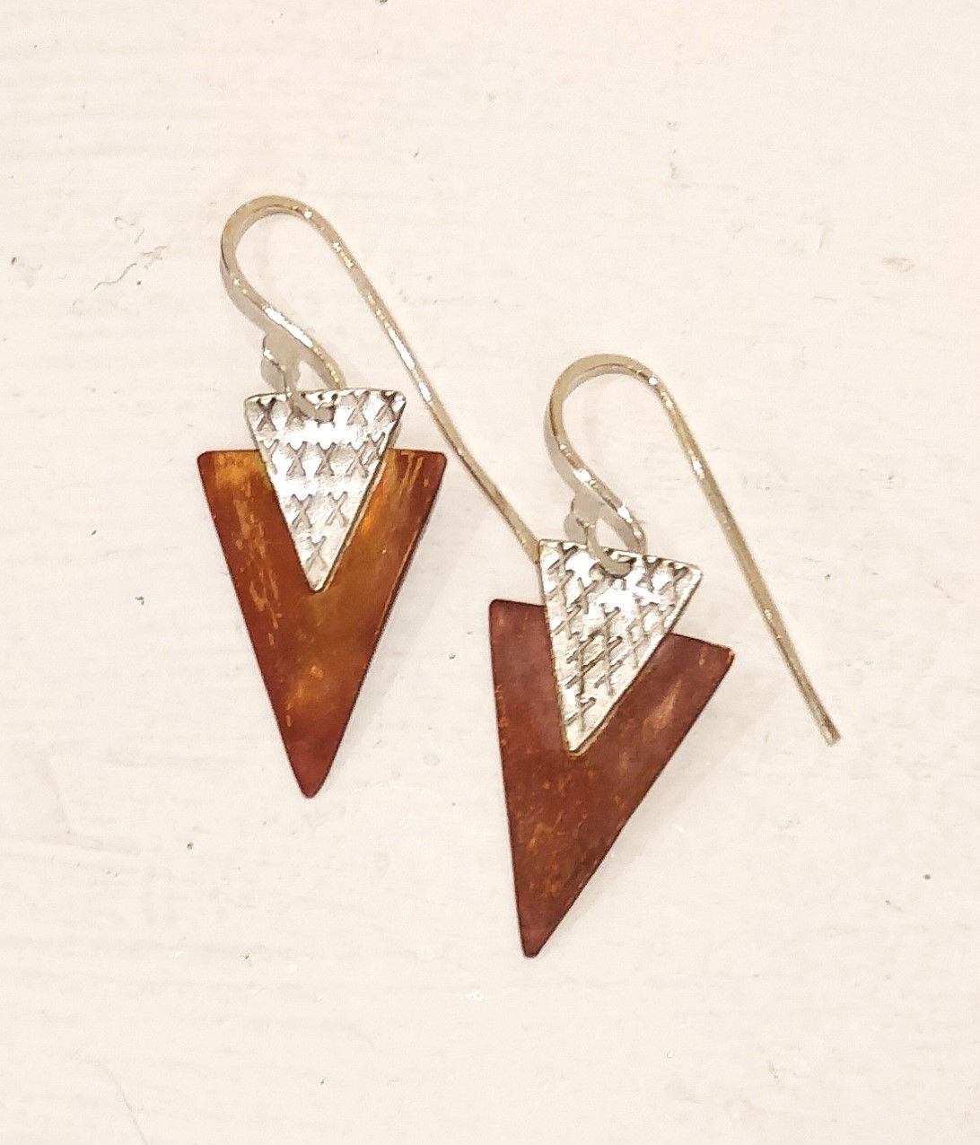 a pair of triangle shaped earrings on a white surface