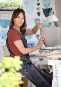 A woman is sitting at a table holding a bowl.