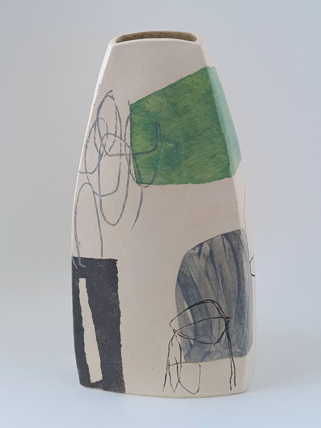 a white vase with a green and black design on it