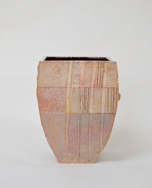 A small beige ceramic vase with subtle pink and tan patterns on a plain white background