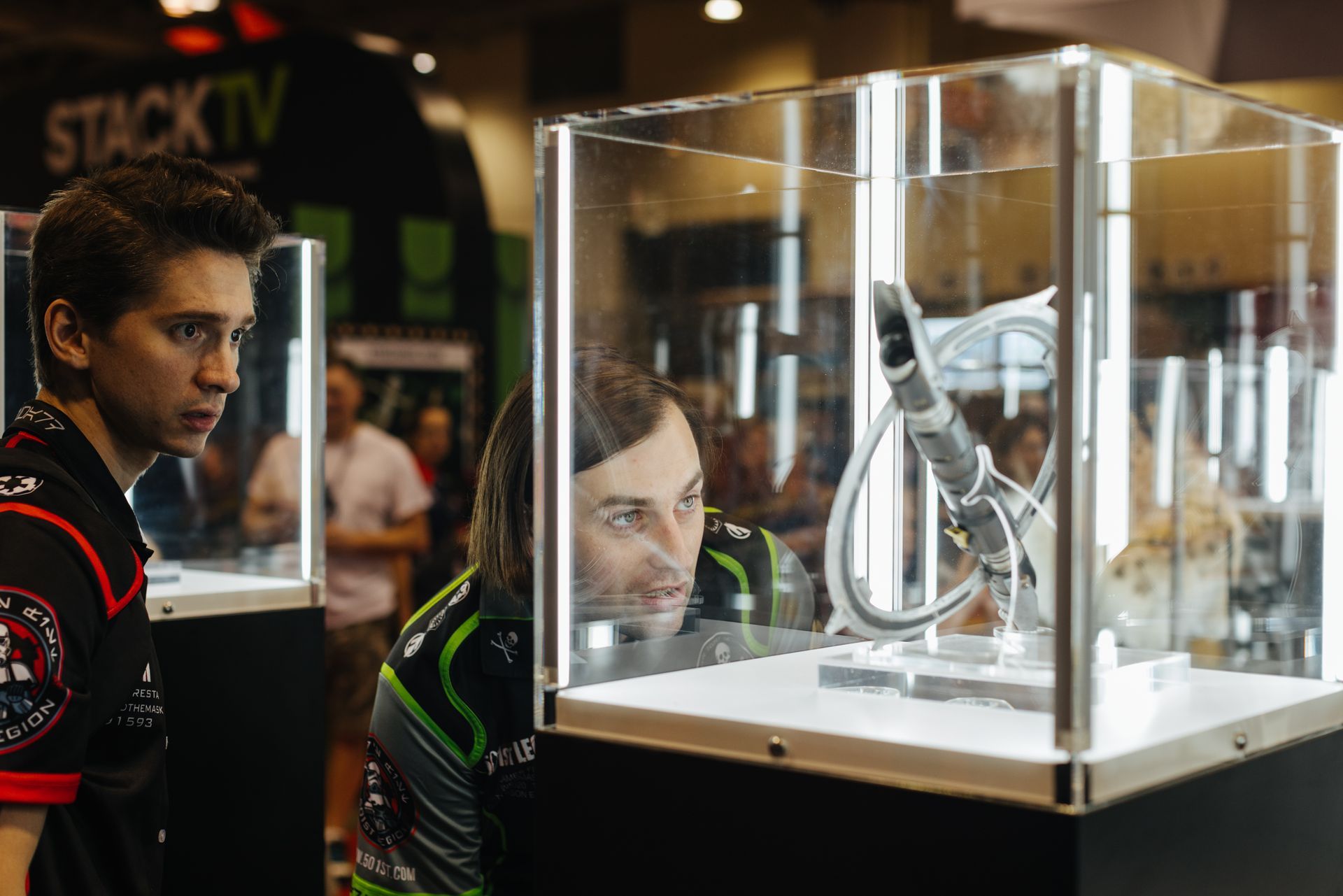 Two men are looking at a display case at a convention.