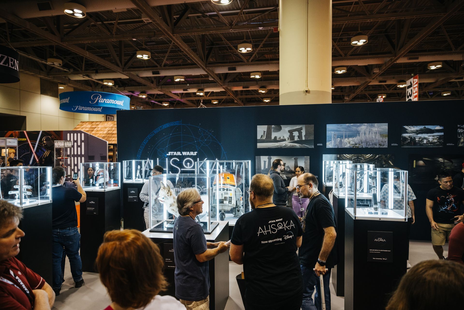 A group of people are standing around a booth at a convention.
