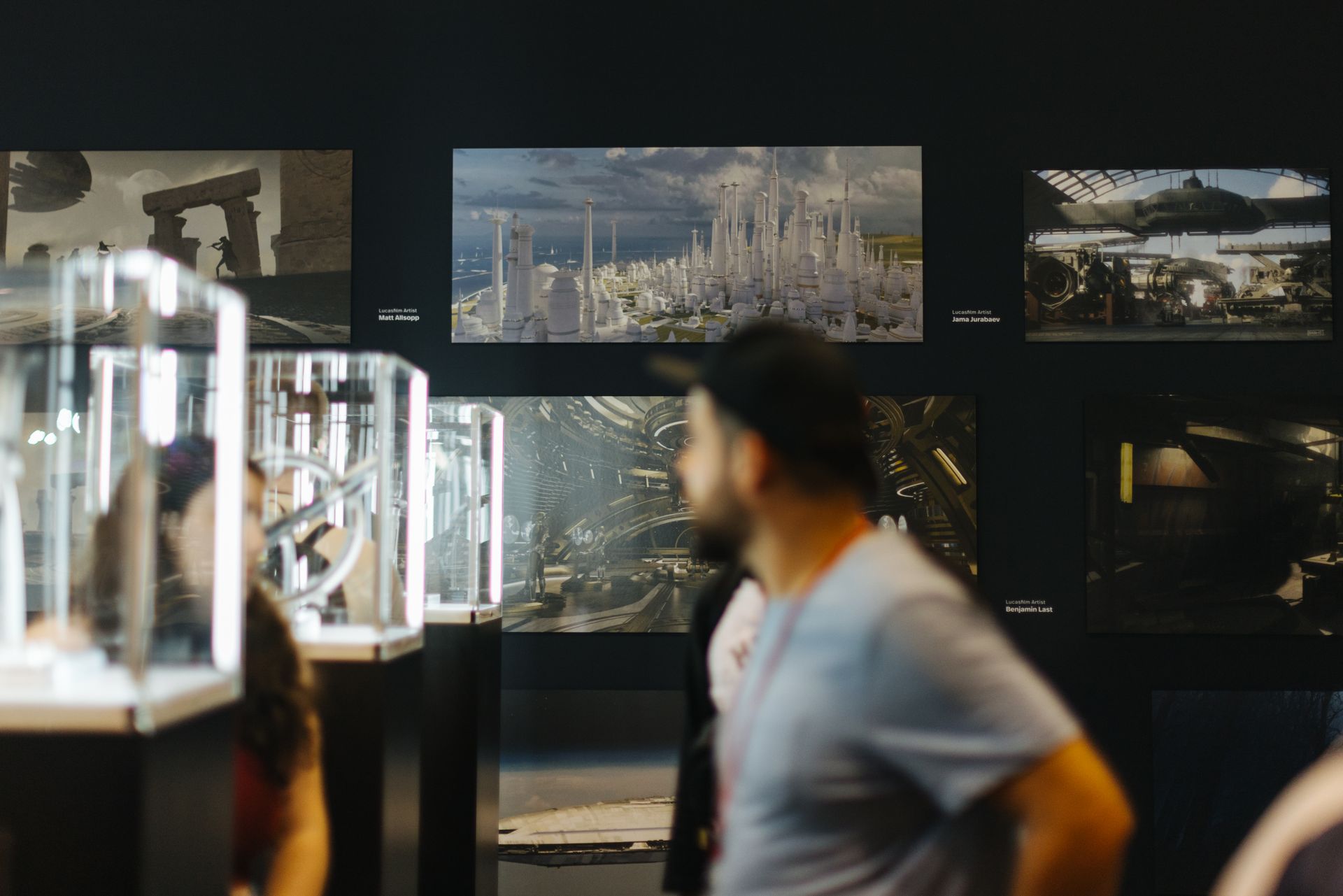 A group of people are looking at pictures on a wall.