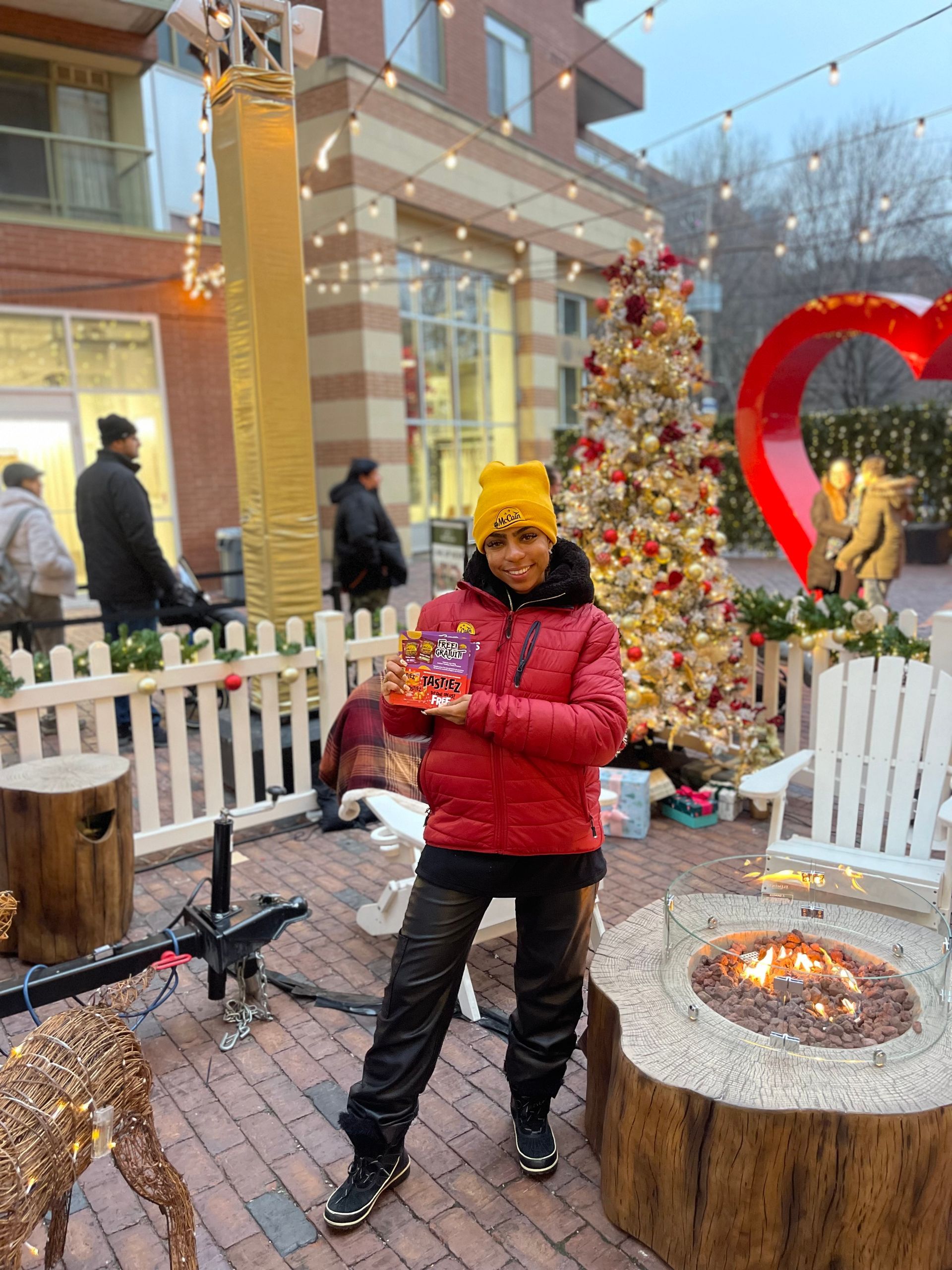 A man in a red jacket is standing in front of a christmas tree holding a candy cane.