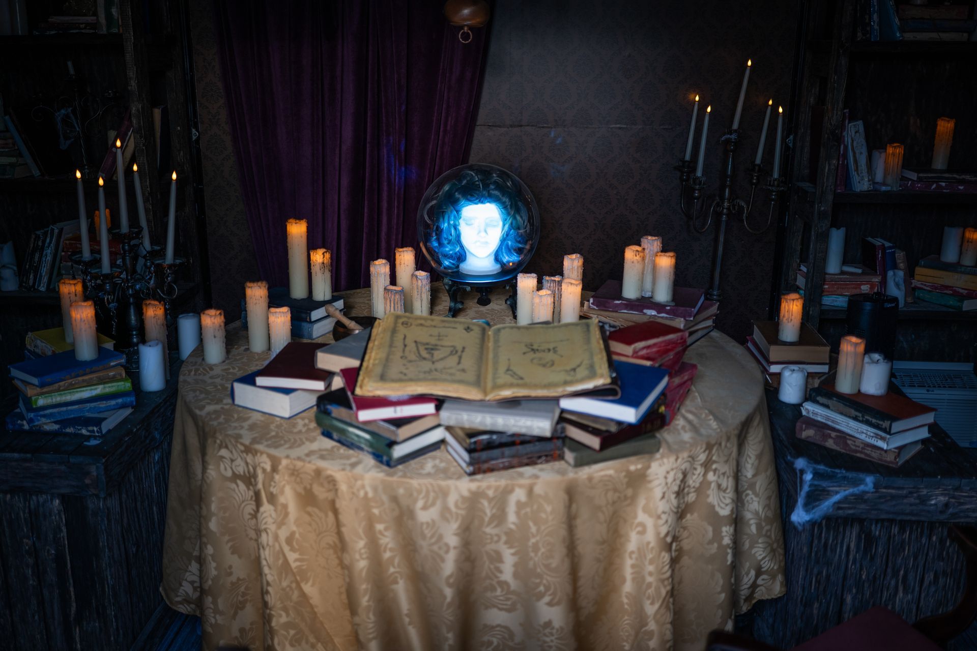 A table filled with books and candles in a dark room.