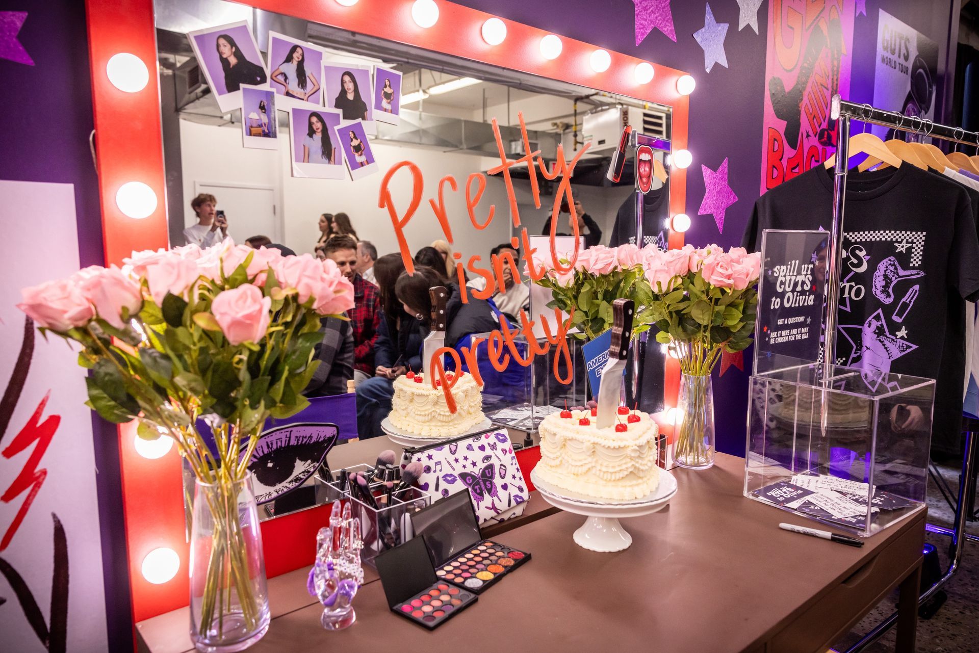A table with flowers and a cake on it in front of a mirror.