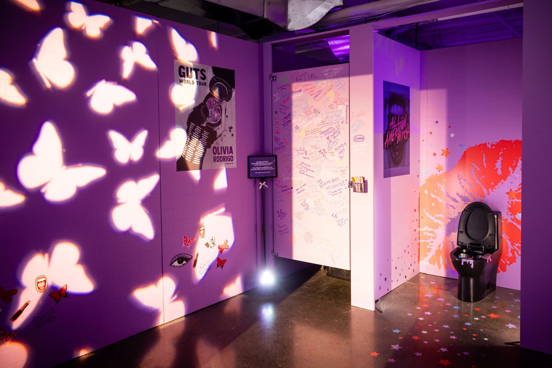 A purple room with a toilet and butterflies projected on the wall.