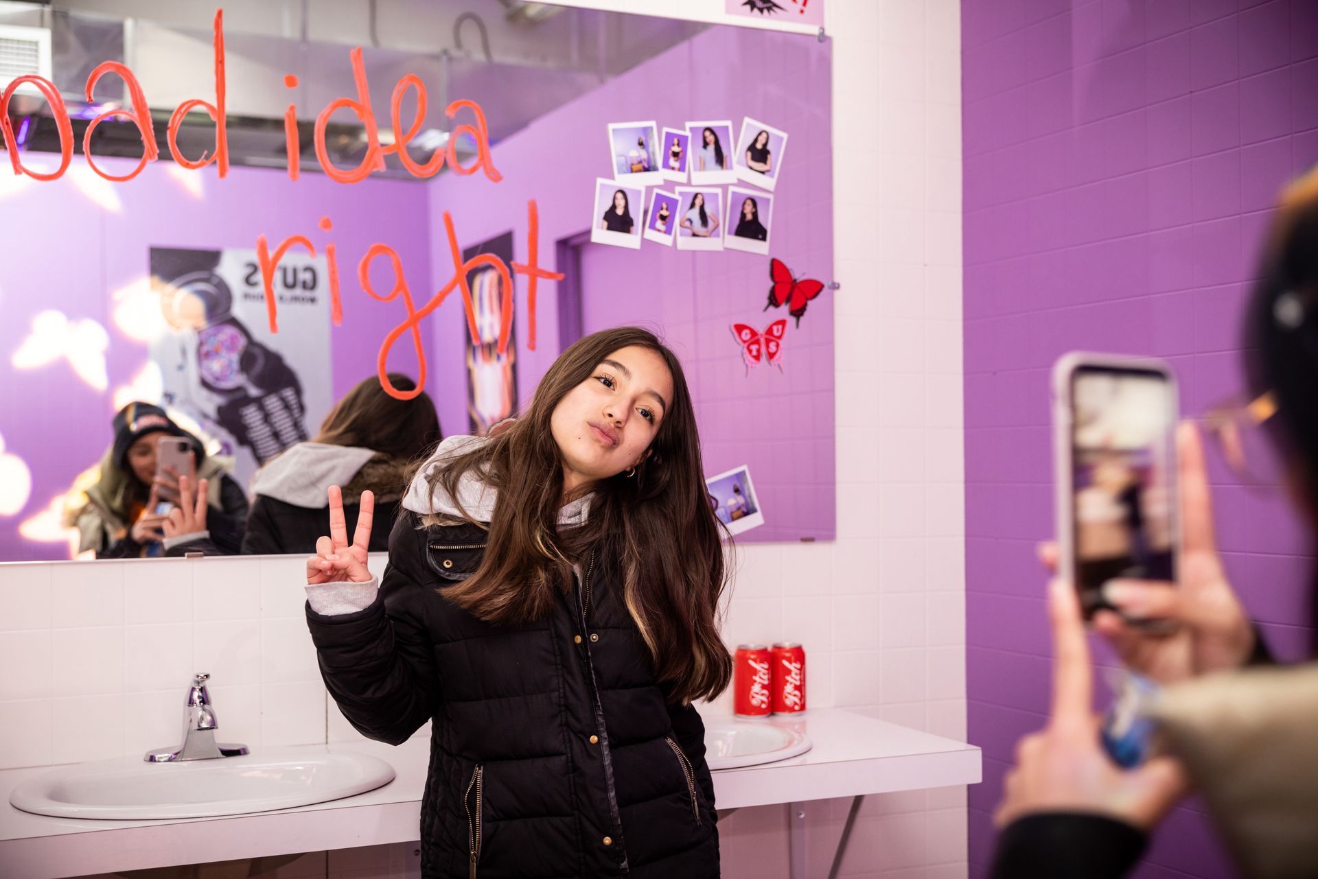 A woman is taking a picture of a girl in front of a mirror.