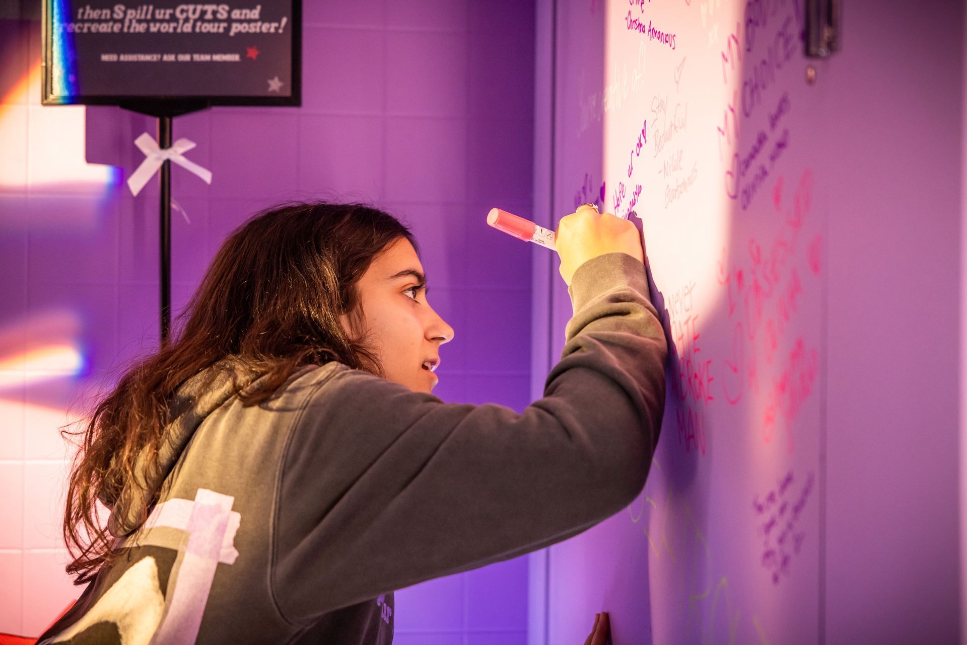 A woman is writing on a wall with a marker.