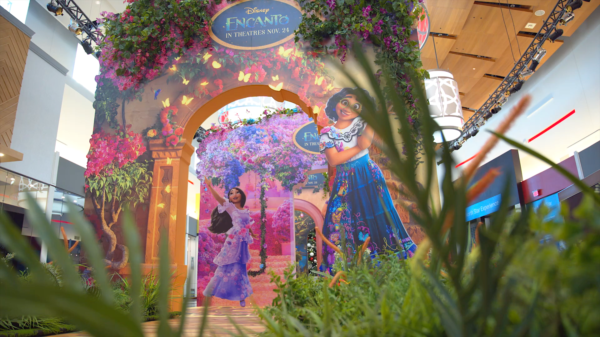 A woman is standing in front of a painting of a princess in a mall.