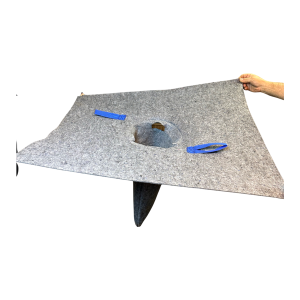 A gray, square-shaped felt protective cover for a tree, with a central hole and blue Velcro straps, held by a hand.